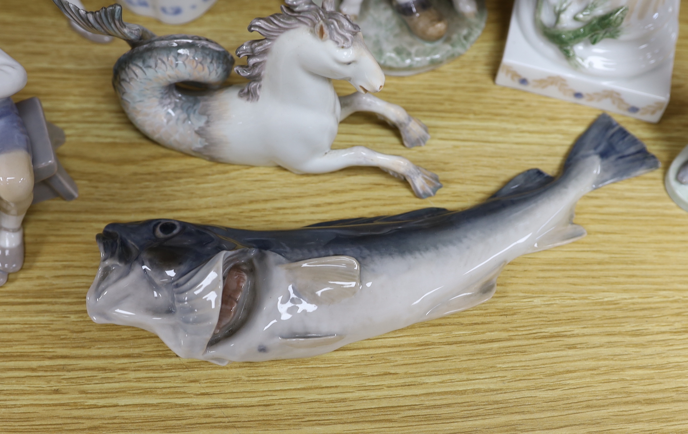 Seven mixed Royal Copenhagen models including children, fish, a fawn, a sailor, a cow and a seahorse (hippocampus), the largest 23cm high
